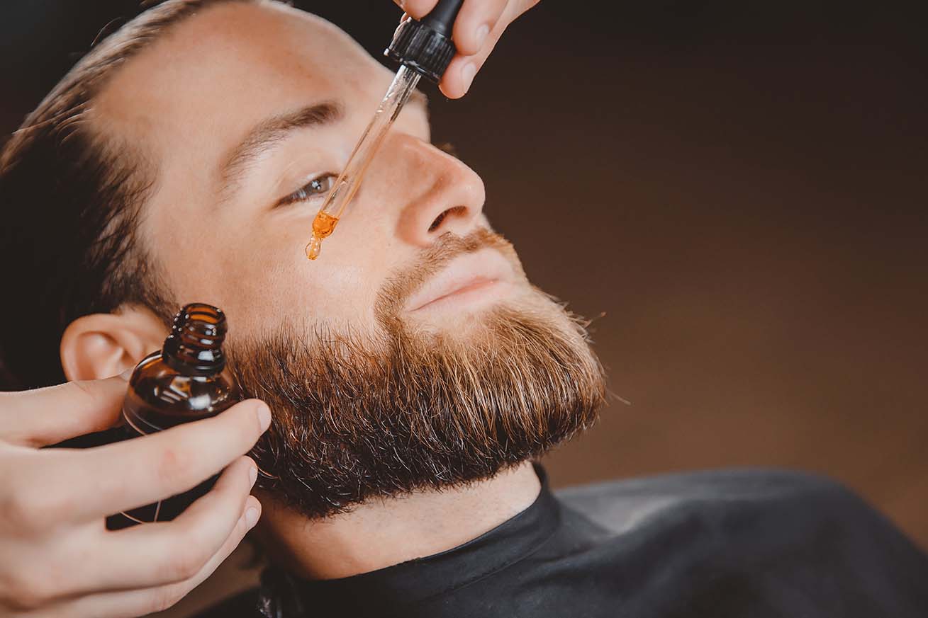 Homme mettant de l'huile sur sa barbe